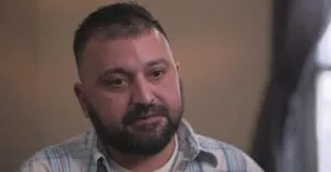 A headshot of a man with short dark hair and a full beard, looking slightly off-camera.