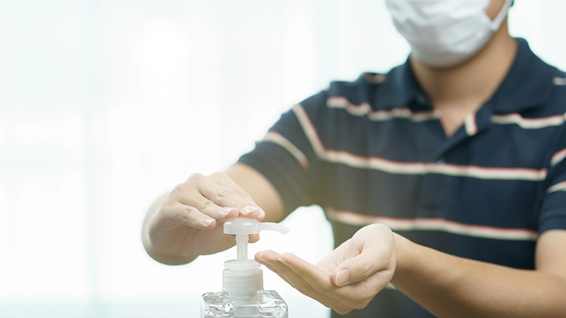 Man wear protective face mask cleaning his hands with sanitizer liquid antibacterial gel.