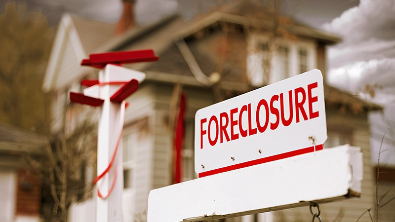 Close-up foreclosure real estate sign in front of house.