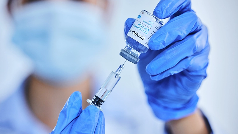 Female medical worker's hand and vaccine bottle with needle for treatment or control for virus, disease and liquid vial.
