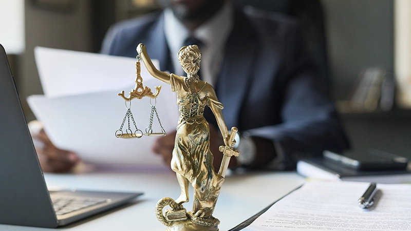 Bronze Lady Justice statue on law office desk with attorney behind.