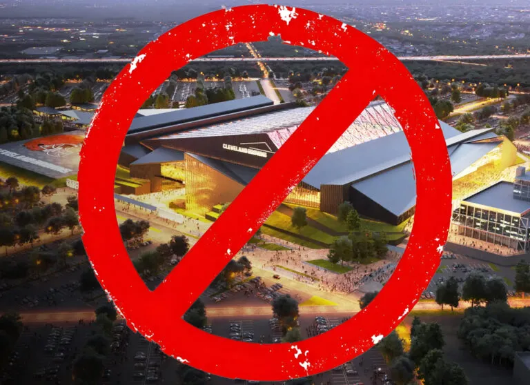 Aerial view of a modern sports stadium complex overlaid with a large red prohibition circle with a diagonal slash across it.