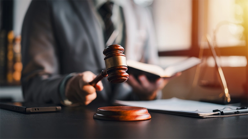 An attorney is reading a book while holding a gavel.