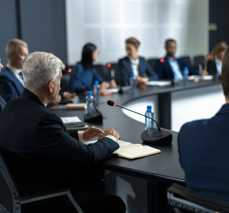 Group of professionals sitting around a curved table during a conference meeting.